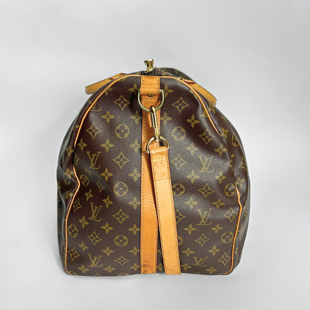 Brown leather bag with gold monogram pattern on a light gray background