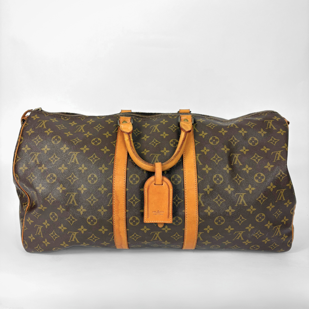 Louis Vuitton monogram travel bag with brown handles on a white background